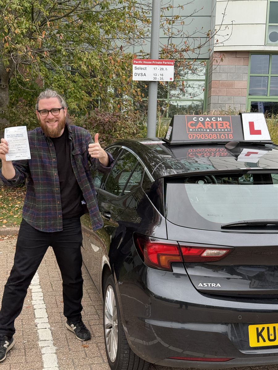 Pete holding his pass certificate next to the CoachCarter car
